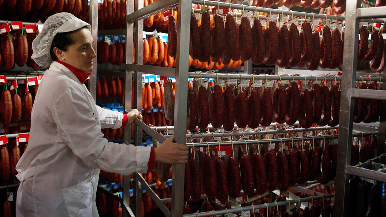 woman moving sausage racks