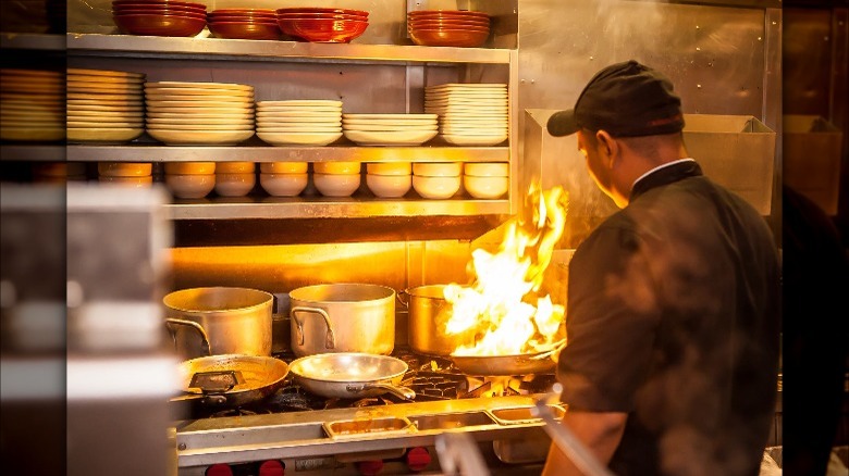 Man in Carrabba's kitchen cooking with high flames