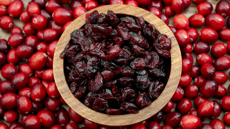 dried cranberries in a wood bowl over a bed of fresh cranberries