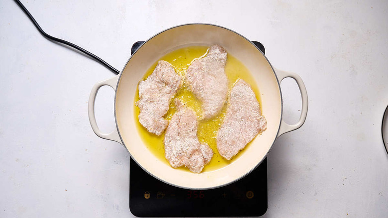 floured chicken in frying pan