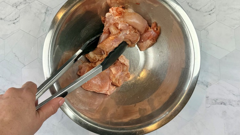 hand holding chicken with tongs