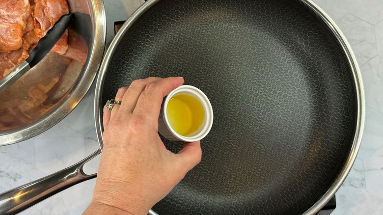 hand pouring oil in pan