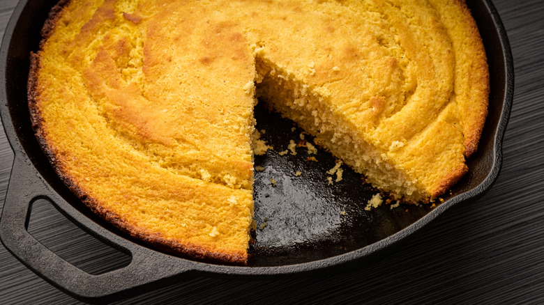 Cornbread in a cast iron skillet with a slice missing