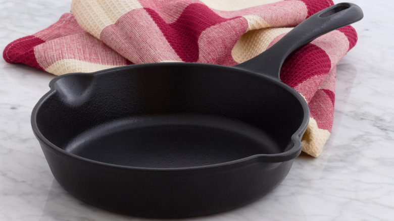 Cast iron skillet in front of a red plaid towel 