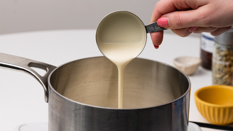 hand pouring cream into a pan 