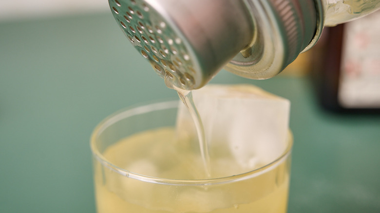 straining cocktail into glass