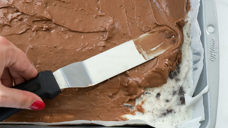 hand spreading chocolate frosting