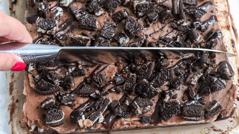 hand slicing frosted brownies