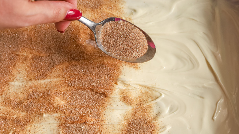 Spoon sprinkling cinnamon sugar over white chocolate