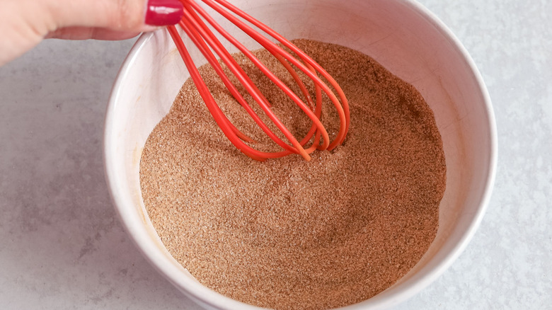 Cinnamon sugar mixture with red whisk in bowl