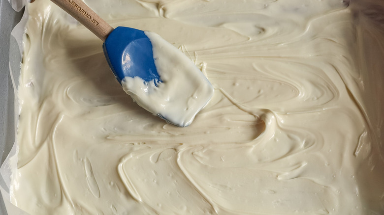 Spatula smoothing white chocolate into pan