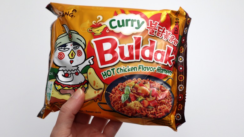 Person holding a pack of Buldak curry ramen