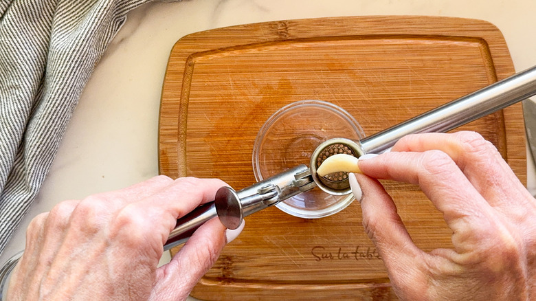 hand adding garlic to press