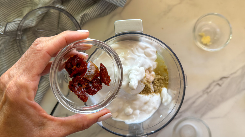 hand adding peppers to processor
