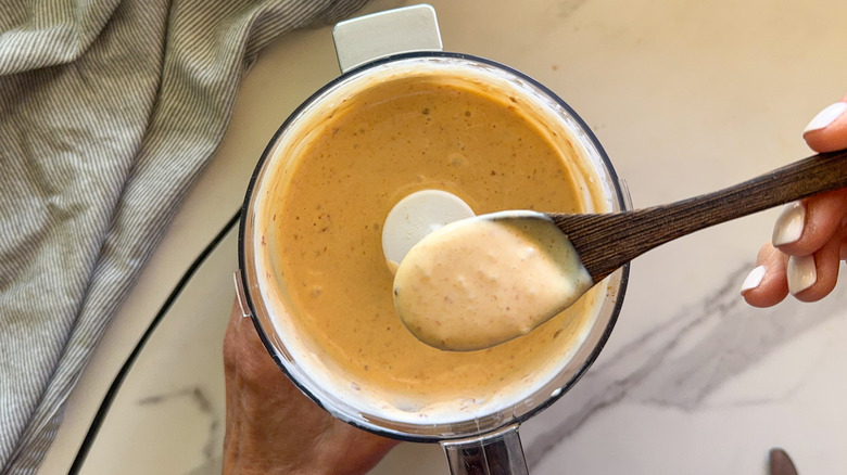 hand holding spoon of sauce
