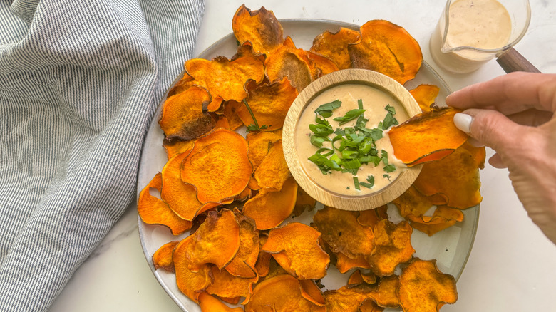 hand dipping chip in sauce