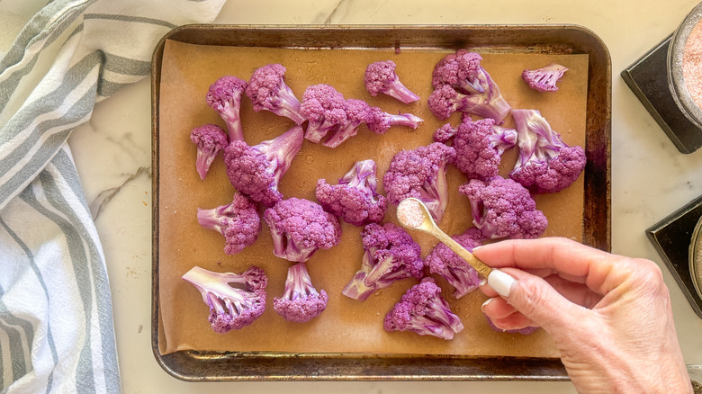 hand adding salt to cauliflower