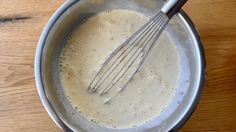 eggs and milk in bowl with whisk