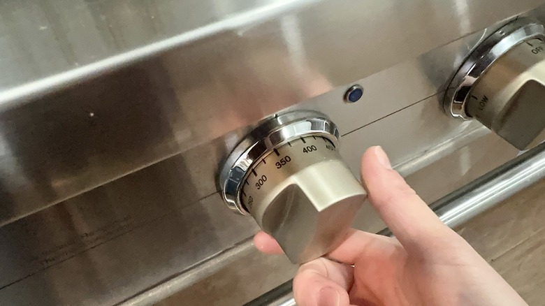 hand turning dial on oven