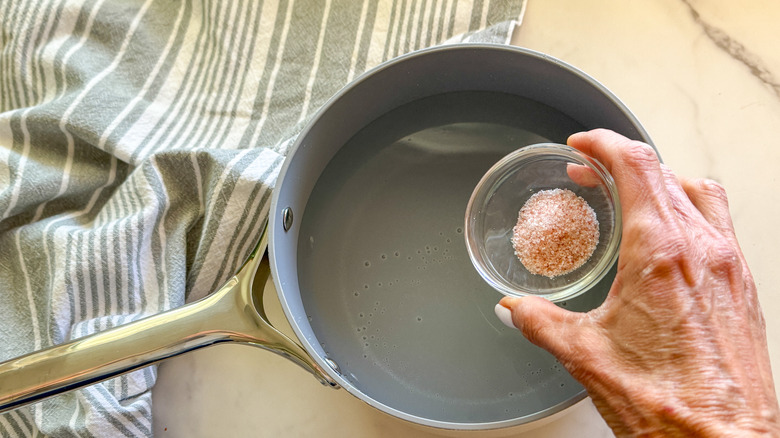 hand adding salt to pot