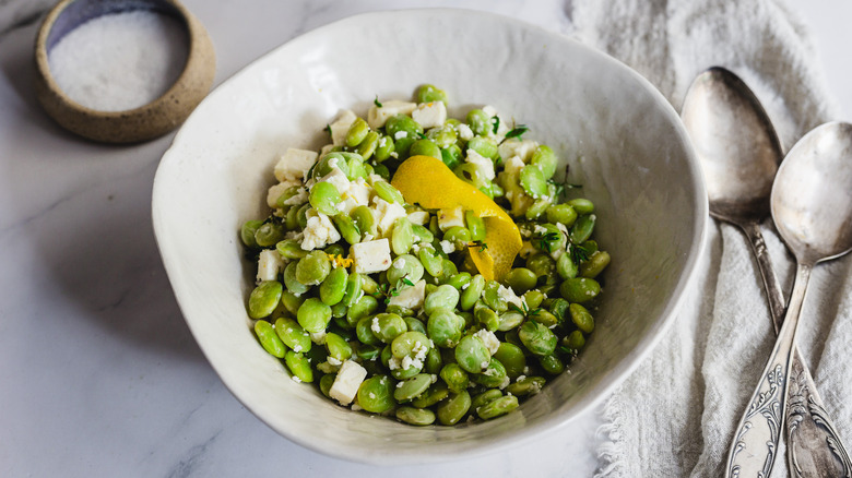 lima beans and feta in bowl with two spoons and salt