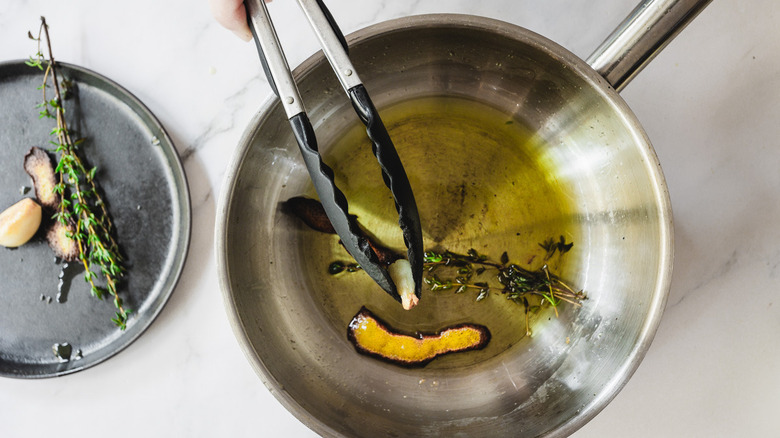 removing garlic from pan with tongs