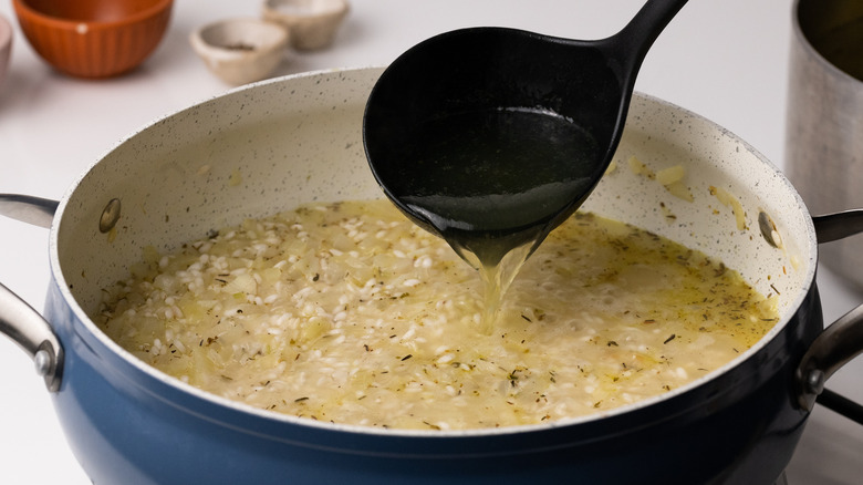 pouring stock into large pan 