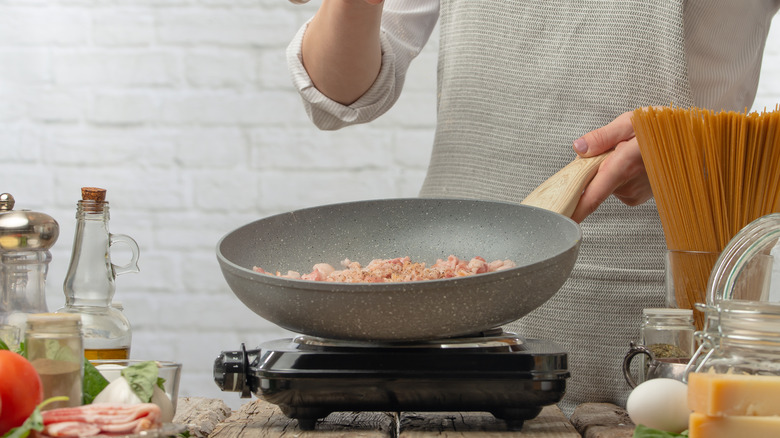 Person cooking pasta in pan 