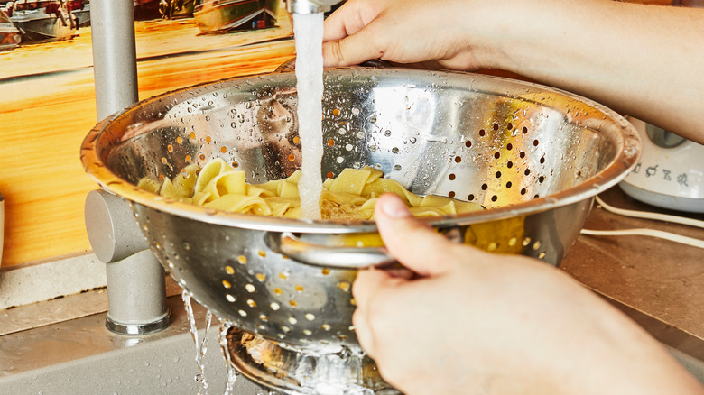 Rinsing pasta in colander sink