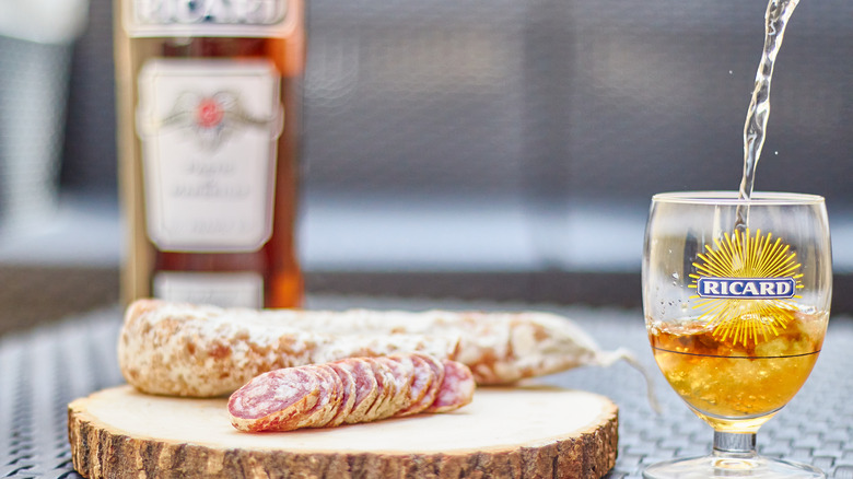Bottle and glass of Ricard pastis with charcuterie on board