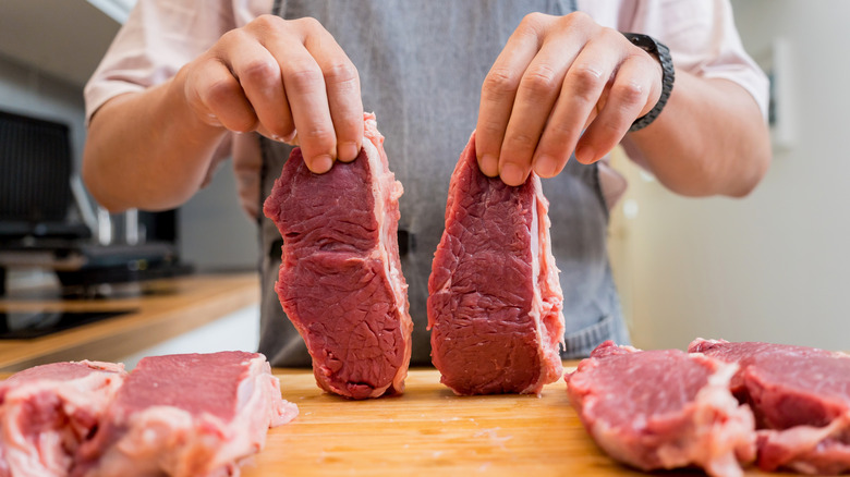 Person holding cuts of beef steak