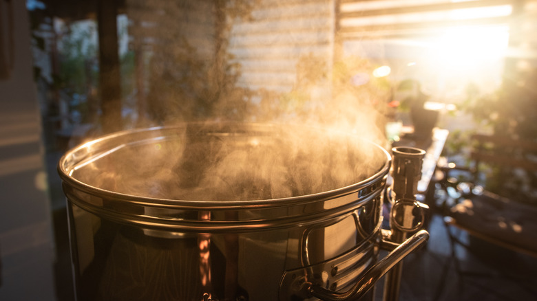 A steaming stainless steel brew pot