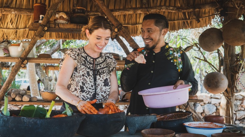 Pati Jinich and a chef cooking in an outdoor kitchen