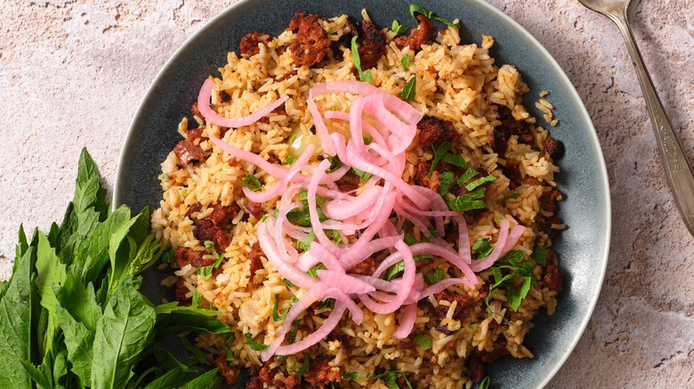 A plate of rice with chorizo and pickled onions