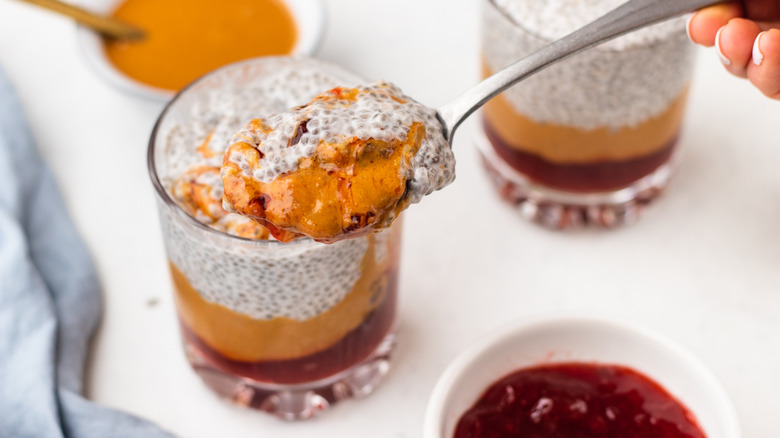 Spooning peanut butter and jam chia pudding from glass