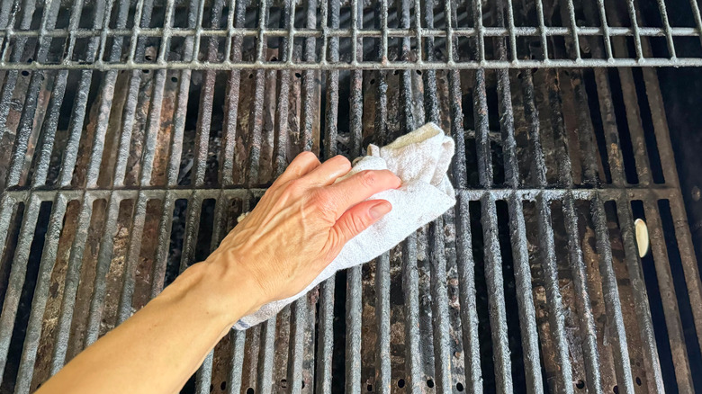 Oiling the grates of a gas grill with a towel