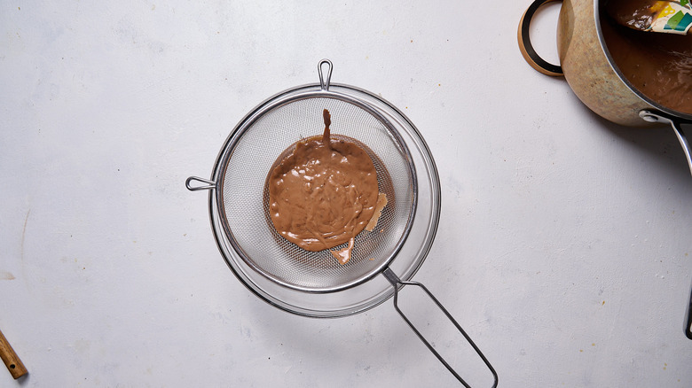 straining pudding into bowl