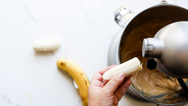 Hand adding banana to mix