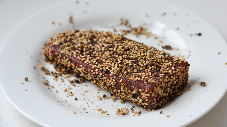 Tuna steak coated in peppercorns and sesame seeds on a plate