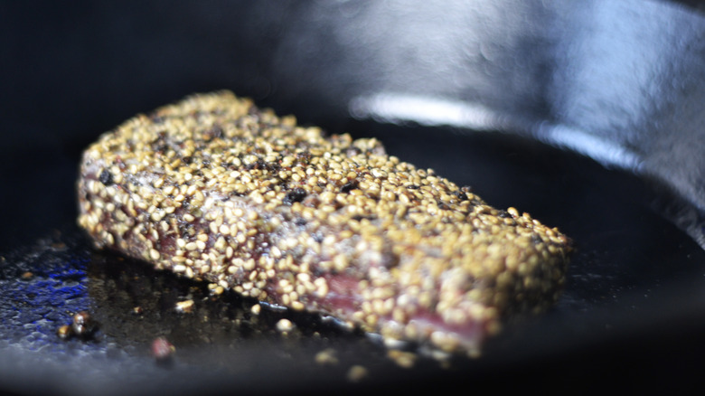 Tuna steak being seared in skillet