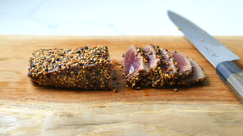 Tuna steak being cut on a cutting board