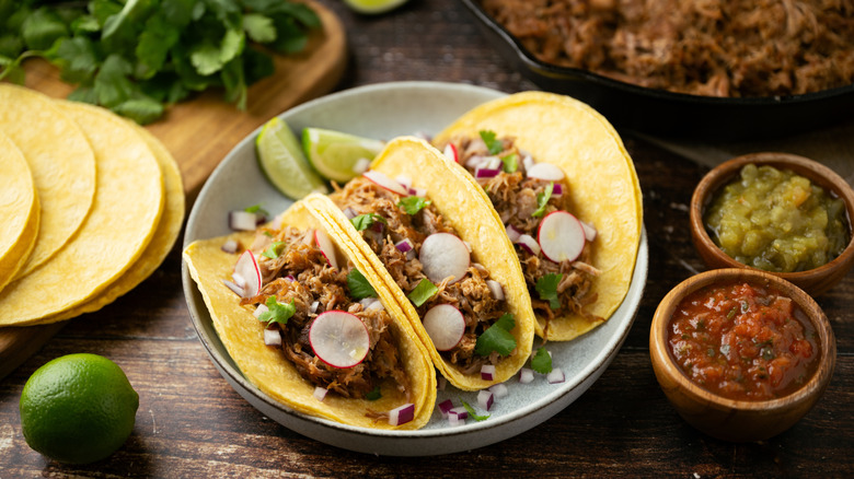 tacos de carnitas with ingredients in bowls