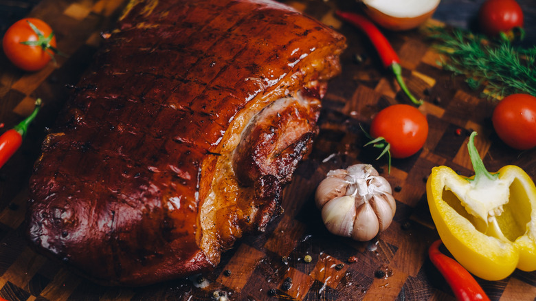 roast pernil of pork with peppers, tomatoes, and garlic clove