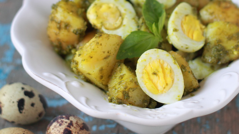 Pesto and egg potato salad garnished with basil