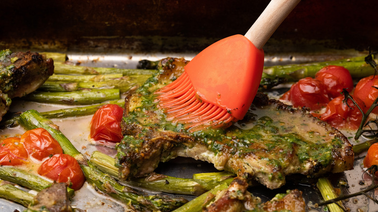 Brushing pork chops with pesto