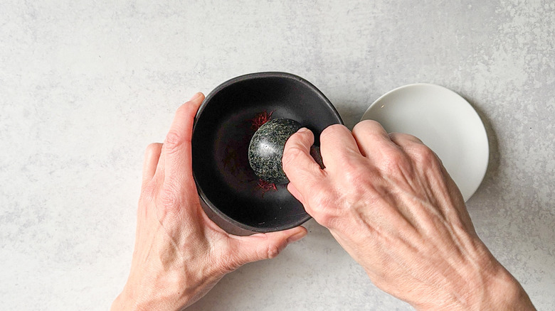 Grinding saffron threads with a mortar and pestle