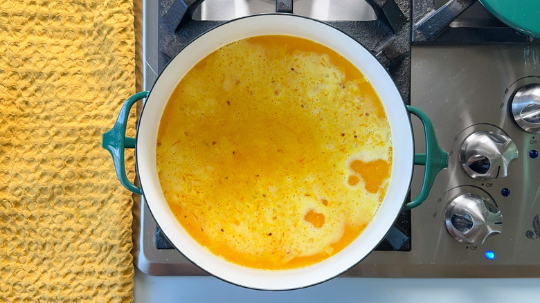 Rice simmering in saffron water in pot on stove top