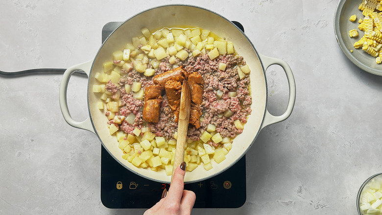 browning chorizo in skillet with potatoes and ground beef