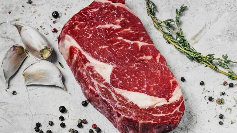 raw ribeye steak surrounded by seasonings