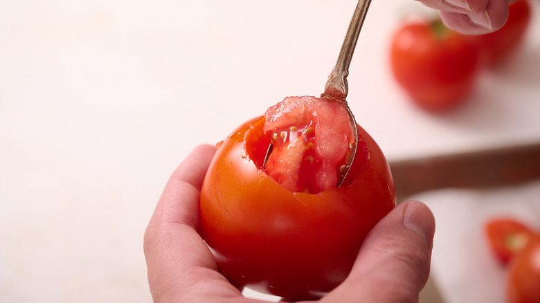 scooping the inside out of the tomato